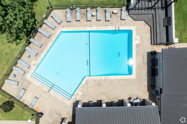 Aerial view of a large rectangular outdoor pool surrounded by lounge chairs on a concrete deck.