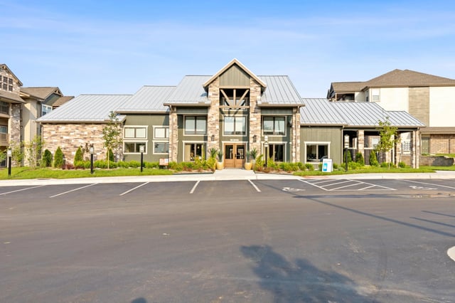 Exterior view of a modern apartment building with landscaping and parking spaces.