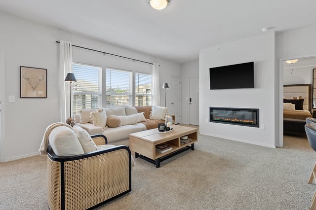 Modern living room with a white sectional sofa, fireplace, and TV.