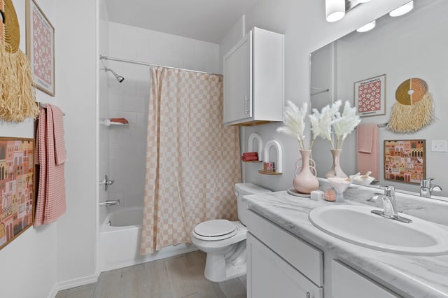 Modern bathroom with marble countertop, white vanity, and a checkered shower curtain.