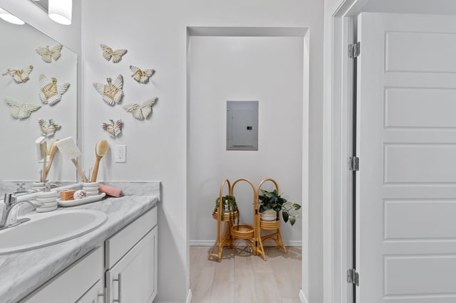 Bathroom vanity with marble countertop and decorative butterfly wall art.