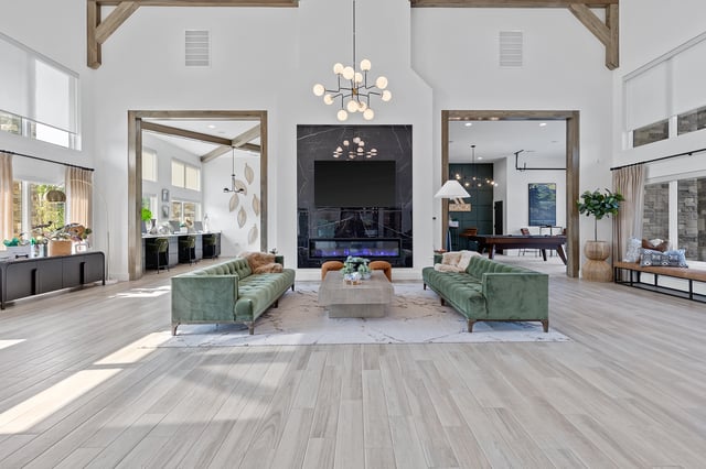 Spacious lounge area with a modern fireplace, two green sofas, and a billiards table visible in the background.