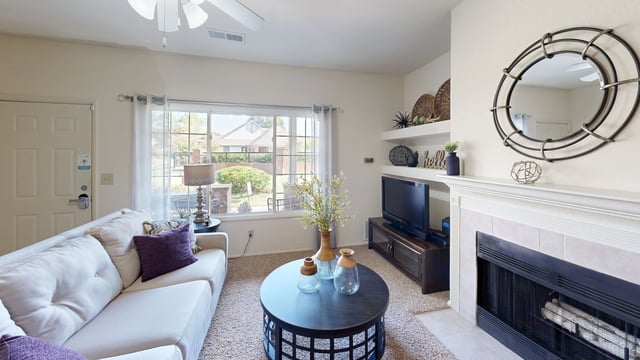 Living room with a fireplace, TV, couch, coffee table, and large window.