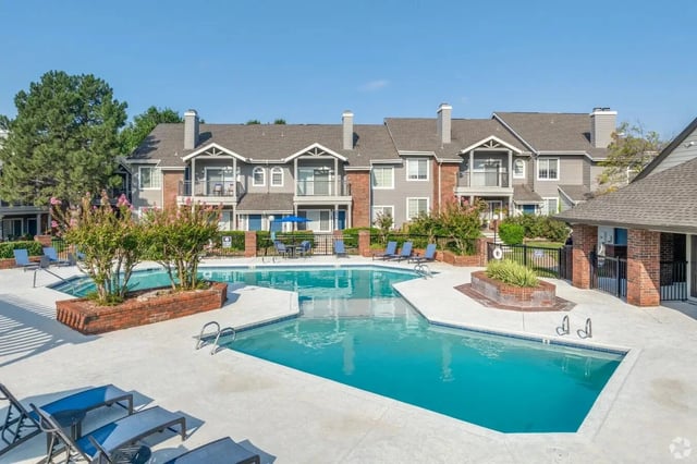 Outdoor pool area of an apartment complex with lounge chairs and brick planters.