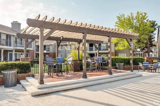 Outdoor seating under a wooden pergola in a residential apartment courtyard.