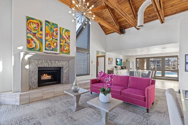 Modern apartment living room with a fireplace, pink sofa, and open layout.