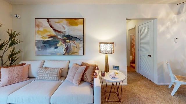 Living room with a sectional sofa, abstract art, and a lamp.