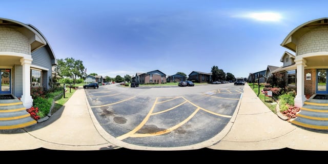 Apartment complex entrance with parking lot and buildings.