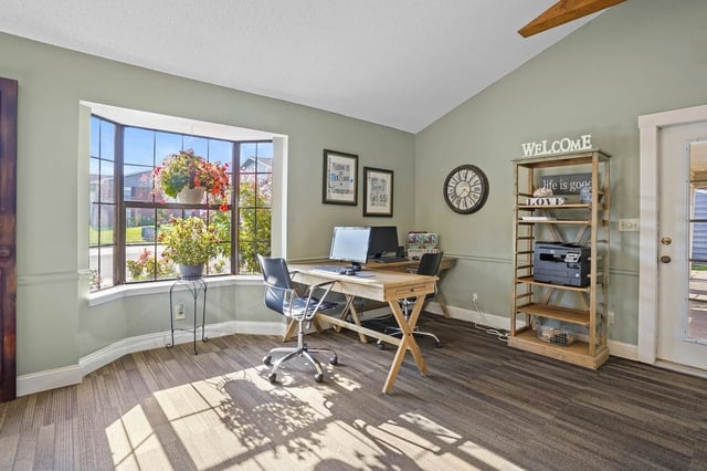 Leasing office workspace with desk, computer, and shelving by a bay window.
