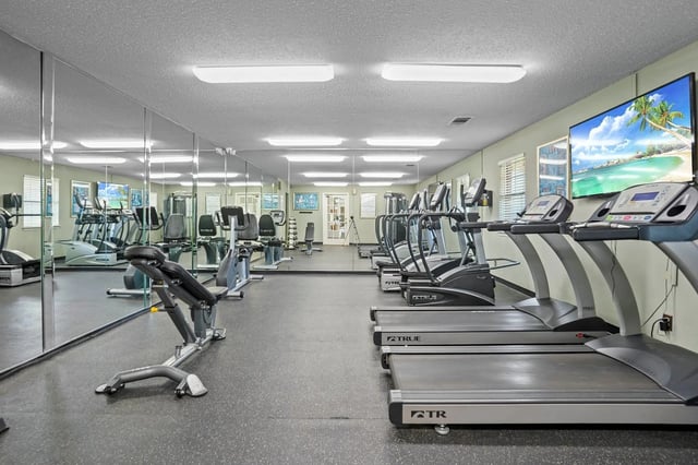 Indoor fitness center with treadmills, ellipticals, and mirrors.