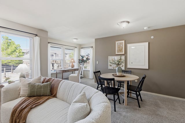Living room with a white sofa, dining table, and desk.