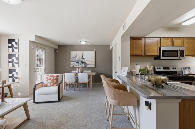 Modern living room and kitchen area with dining table, bar seating, and updated appliances.