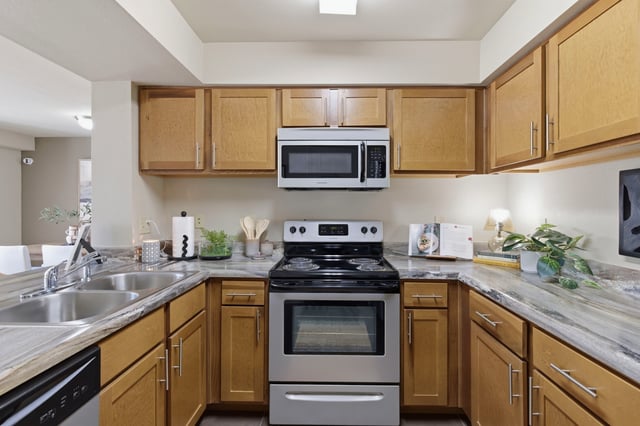 Modern kitchen with light wood cabinets, stainless steel appliances, and granite countertops.