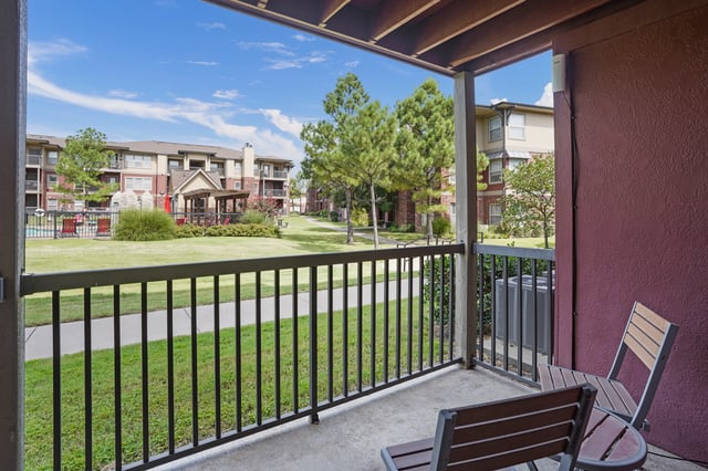View from balcony of apartment complex courtyard with pool and lounge chairs.