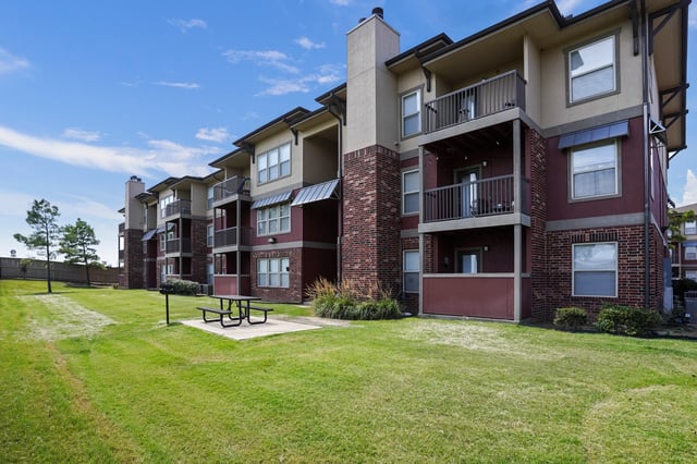 Exterior of apartment building with balconies and picnic area.