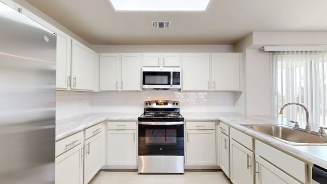 Modern kitchen with white cabinets, stainless steel appliances, and granite countertops.