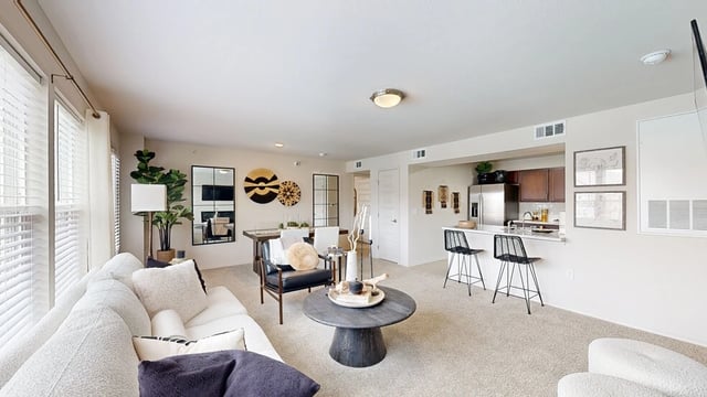 Modern living room and kitchen area with a sectional sofa, dining table, and kitchen island.