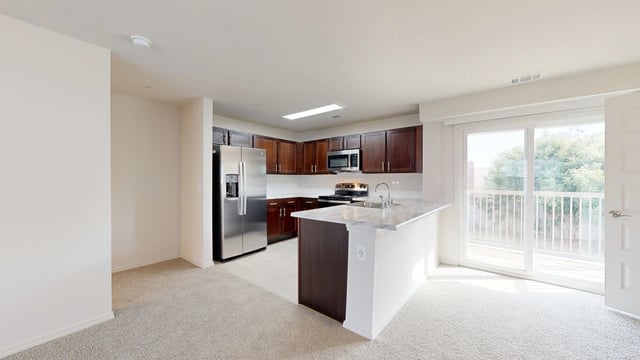 Modern kitchen with stainless steel appliances, dark wood cabinets, and a marble-top island.