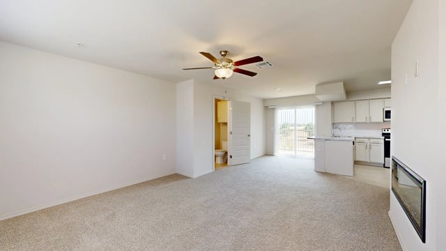 Living room and kitchen area with white cabinets, island, and carpet flooring.