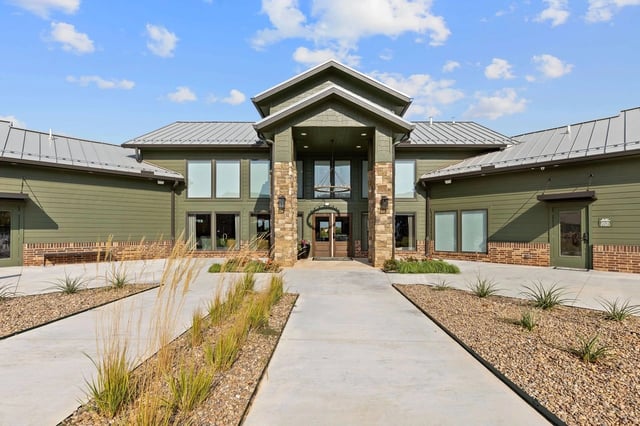 Exterior of a modern apartment building with a grand entrance and landscaping.