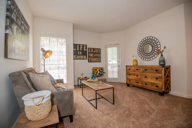 A living room with a grey couch, a coffee table, and a wooden chest of drawers.