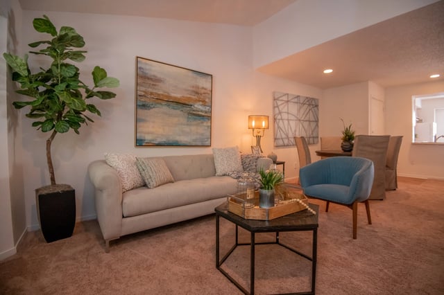 A living room with a couch, chair, and a painting on the wall.