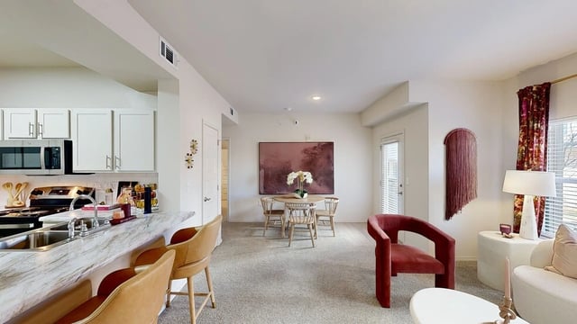 Modern kitchen and living area with island seating and dining table.