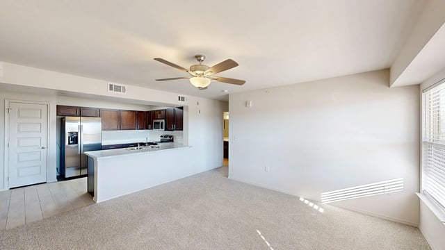 Living room and open kitchen with stainless steel appliances and dark wood cabinets.