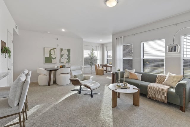 Bright living room with large windows, neutral furnishings, and a green sectional sofa.