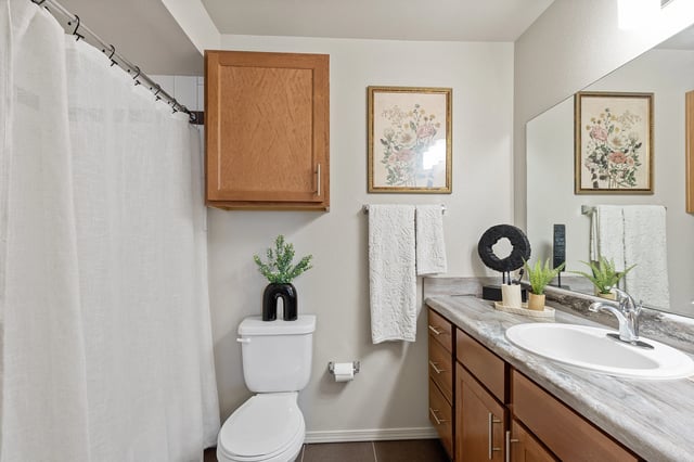 A bathroom with a toilet, sink, and a mirror.