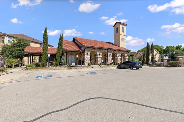 A parking lot with a building and a car.