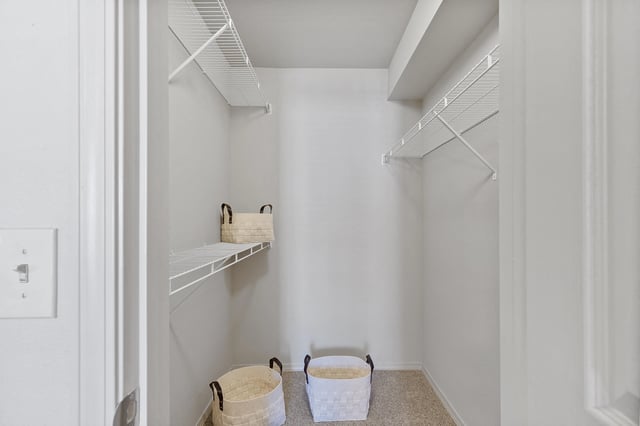 Empty walk-in closet with white wire shelving and storage baskets.