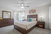Bedroom with a queen-size bed, dresser, nightstand, and ceiling fan.