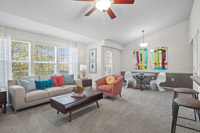 Spacious living and dining area with a sofa, armchair, dining table, and bar seating.