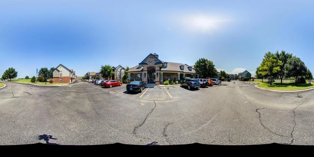 Apartment building exterior with parking lot and trees.