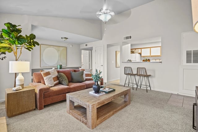 Living room with sofa, coffee table, and view into kitchen.