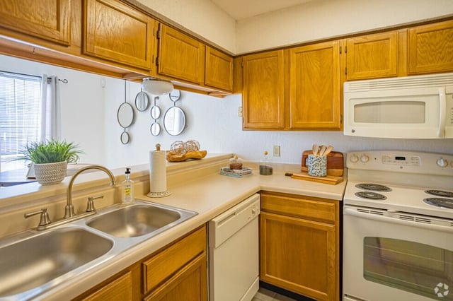 Kitchen with light wood cabinets, white countertops, double sink, and a white stove.