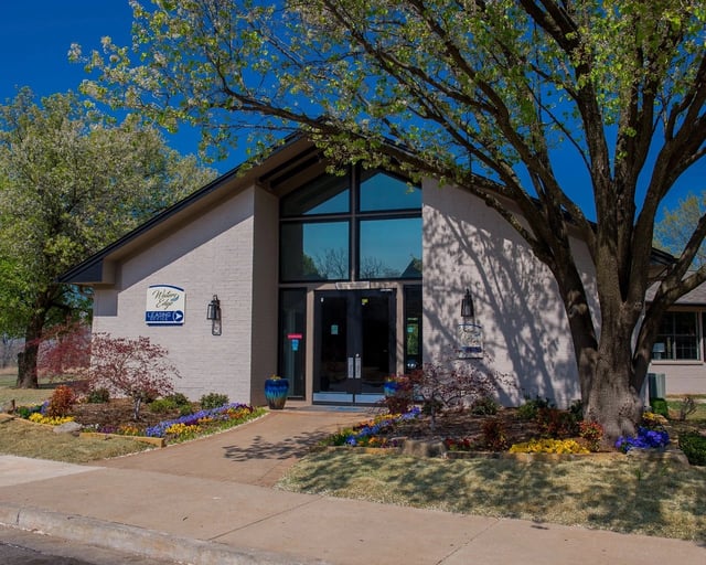 Leasing office entrance with glass doors, brick facade, and landscaped plants.