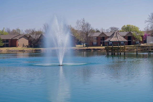 Lake with fountain, gazebo, and apartment buildings in the background.