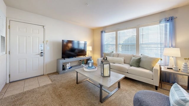 Living room with a beige sofa, coffee table, TV, and a large window.