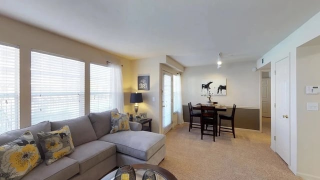 Living room and dining area with sectional couch and table with chairs.