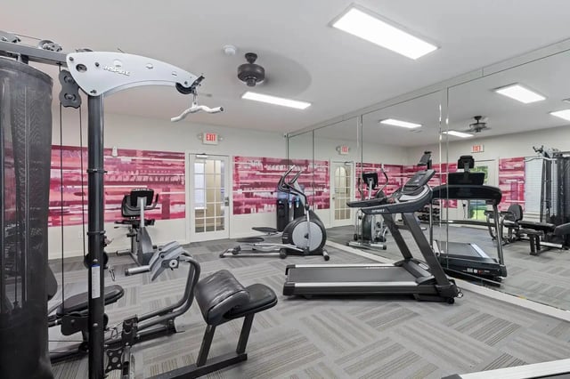 Indoor fitness center with treadmills, ellipticals, weight machines, and mirrors.