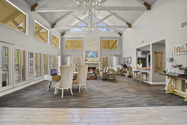 Spacious community lounge with vaulted ceiling, chandelier, fireplace, and varied seating.