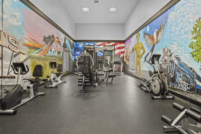 Interior of a community gym with cardio machines and wall murals.