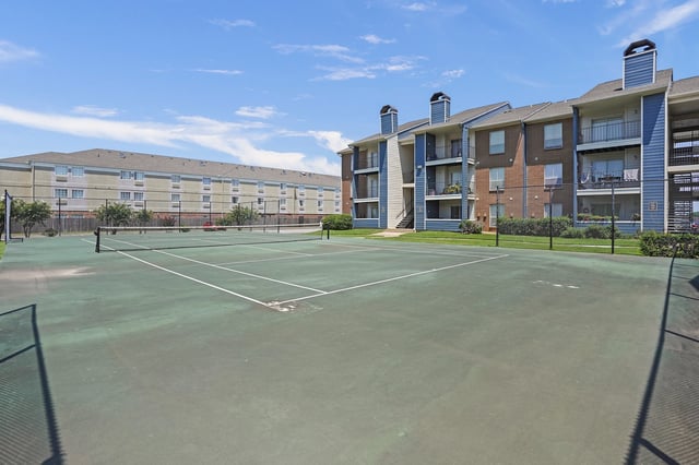 Tennis court with apartment buildings in the background