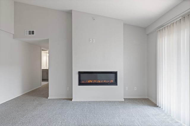 Modern living room with a sleek electric fireplace and large vertical blinds.