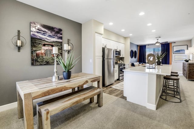 Dining area and kitchen in an apartment with stainless steel appliances and a large island.