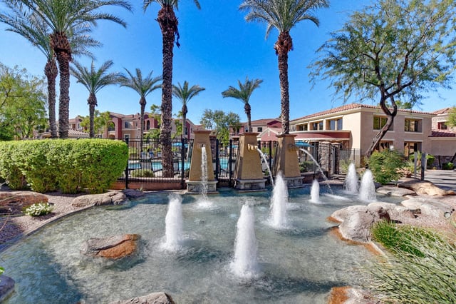 Fountain with palm trees and apartment buildings in the background.