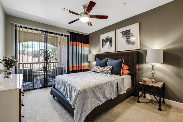 Bedroom with a queen-size bed, nightstand, dresser, and balcony access.