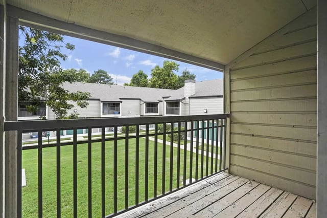 Balcony view overlooking a grassy courtyard with beige apartment buildings.